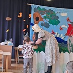 Chłopiec pomaga aktorom na scenie podczas teatrzyku.