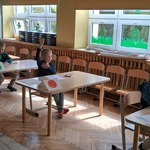 Dzieci siedzą przy stolikach i wykonują kartę pracy.