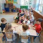 Dzieci siedzą przy stolikach.