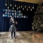 Dziewczynka śpiewa i gra na dzwoneczkach.