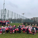 Dzieci z grupy 7_8_9_10 na boisku szkolnym z czerwonymi balonikami