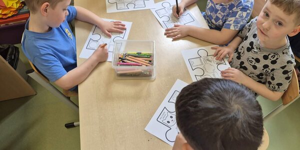 Dzieci z grupy 10 podczas kolorowania puzzli.jpg