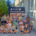 dzieci pozują na tle napisu dzień przedszkolaka